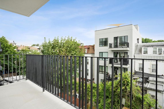 View from a balcony overlooking nearby residential buildings and trees.