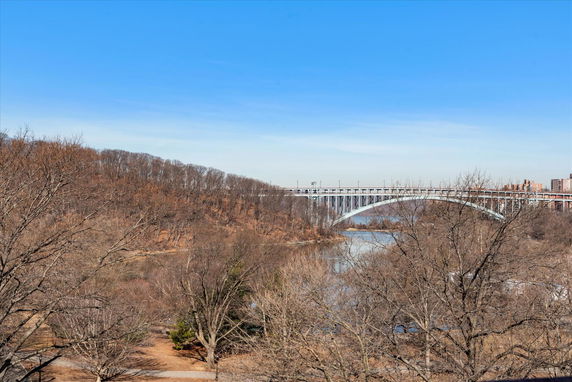 Panoramic view of a bridge crossing over a river with surrounding woodland area.