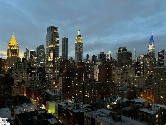 Panoramic view of a city skyline at dusk with illuminated skyscrapers.
