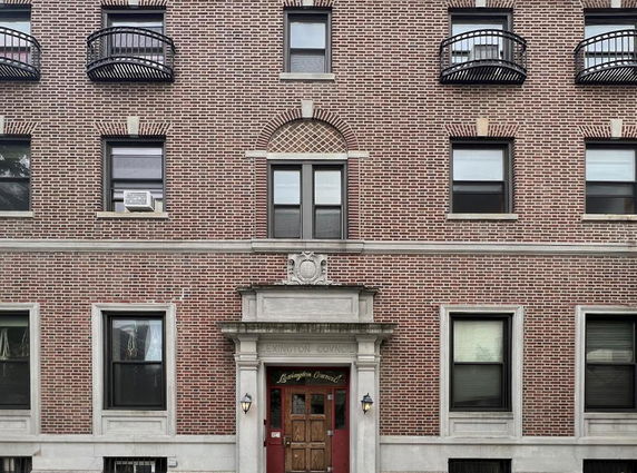 Front view of a brick apartment building with multiple windows and a central entrance.