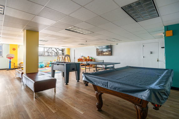 Indoor recreation room with seating, table tennis, and children's play area.