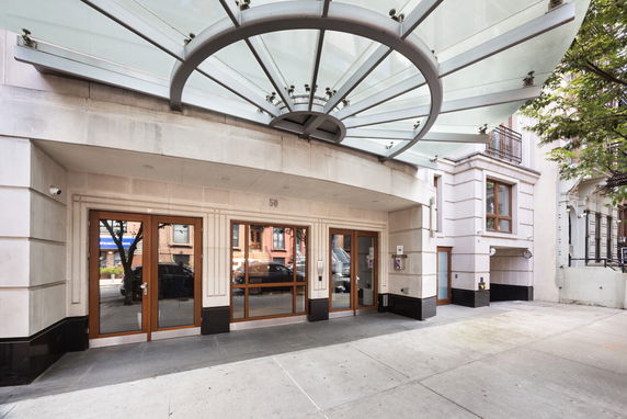Front view of a building with a glass canopy and wooden-framed entrance doors.