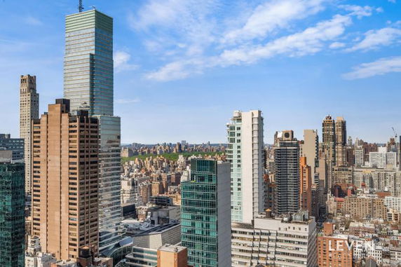 Panoramic view of a city skyline with multiple high-rise buildings under a blue sky.