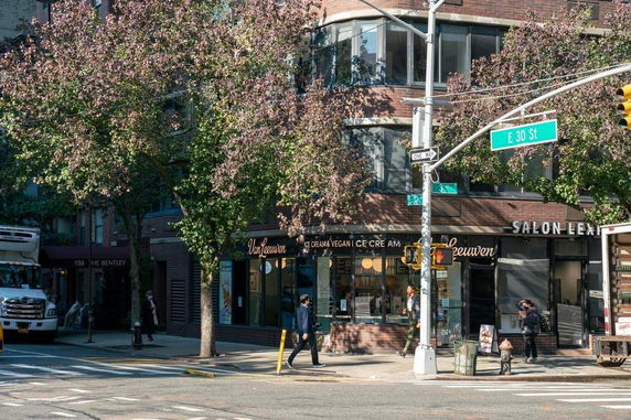 Front view of a building with an ice cream shop and a salon on a street corner.