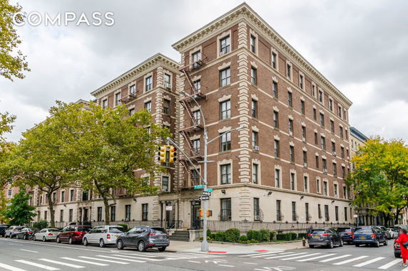 Front view of a multi-story brick apartment building on a street corner.