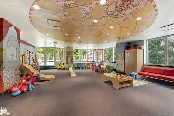 Indoor play area with colorful murals, play equipment, and seating.