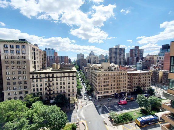 Panoramic view of a cityscape with multiple buildings and a busy street intersection.