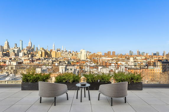 Rooftop balcony with chairs overlooking cityscape.