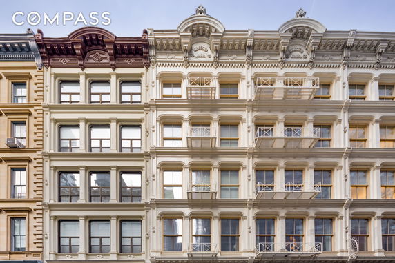 Front view of two adjacent multi-story buildings with decorative facades and large windows.