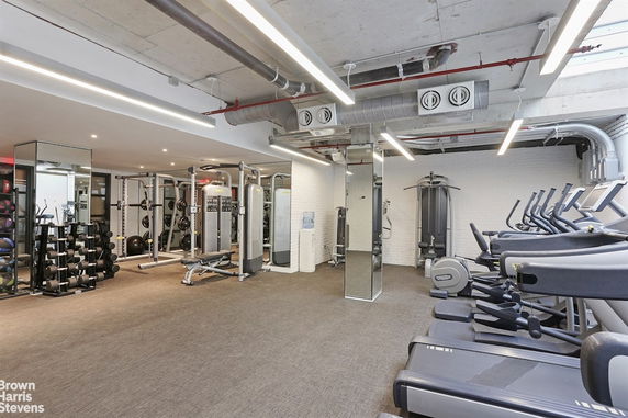 Indoor gym with modern exercise equipment and mirrored walls.