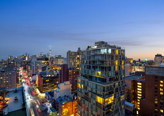 Panoramic view of city buildings at dusk with lights on.