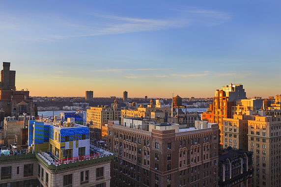 Panoramic view of a cityscape with multiple buildings at sunset.