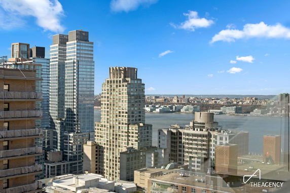 Panoramic view of a cityscape with several high-rise buildings and a river in the background.