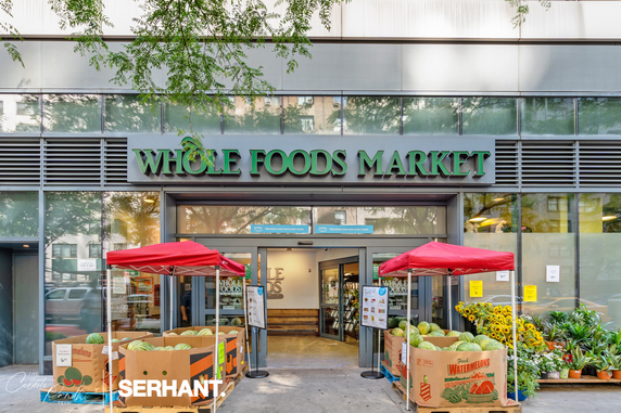 Front view of a Whole Foods Market with entrance and outdoor produce display.
