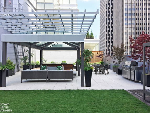 Rooftop area with pergola, seating, dining table, and barbecue grill.