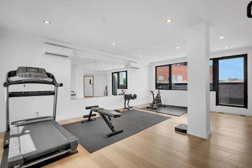 Indoor gym area with exercise equipment including a treadmill, bench, and weights.