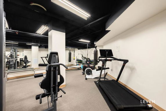 Interior view of a gym with exercise equipment including a treadmill and weight machines.