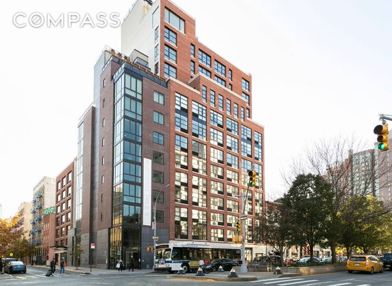 Front view of a multi-story urban apartment building with large windows.