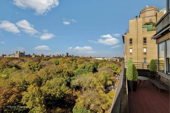 View from a building's balcony overlooking a cityscape and a large park with trees.