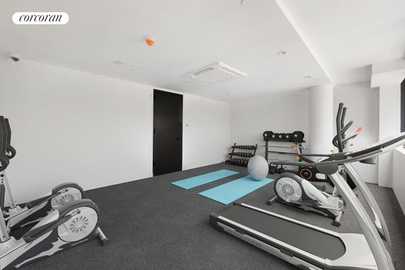 Interior view of a gym room with exercise equipment and mats.