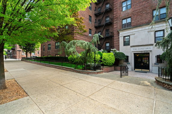Front view of a multi-story brick building with landscaped entrance.