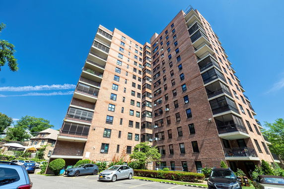 Front view of a multi-story brick apartment building with balconies.