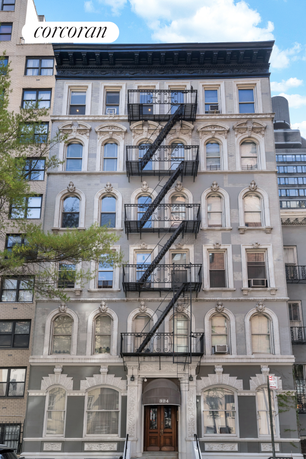 Front view of a multi-story building with decorative arched windows and fire escapes.