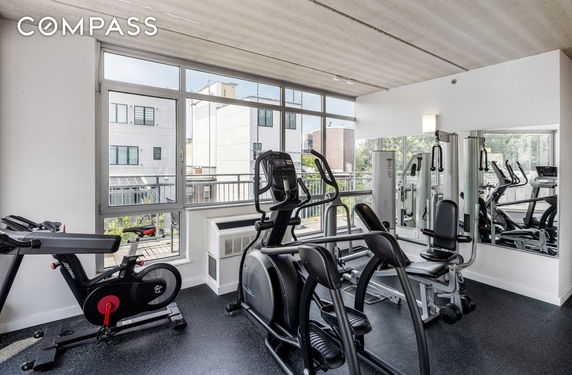 Indoor gym area with exercise equipment and large windows.
