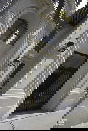 Front view of a building entrance with ornate architectural details and lamps.