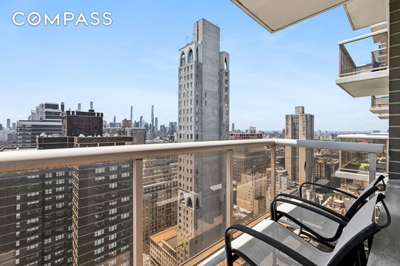 Panoramic view from a high-rise balcony overlooking a cityscape with skyscrapers.