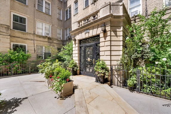 Front view of a building entrance with ornate black doors and a stone facade.