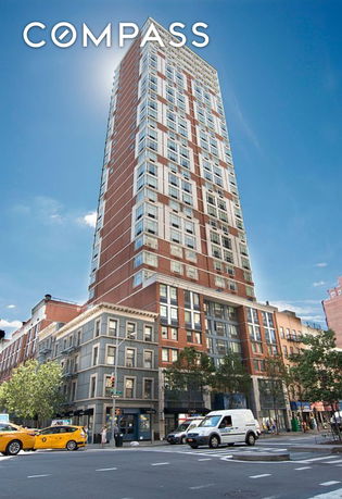 Front view of a tall multi-story building with a brick and glass facade.