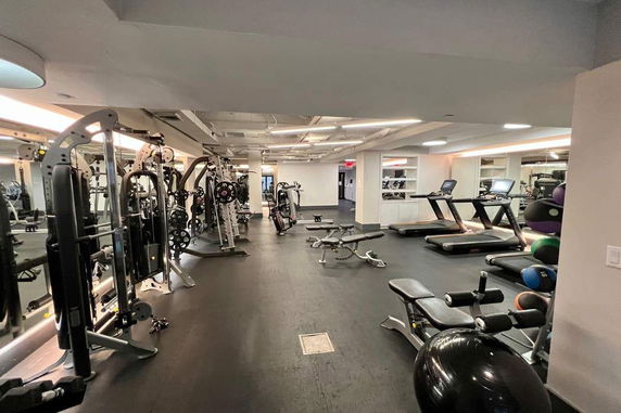 Indoor gym area with various exercise equipment, including treadmills, weight machines, and benches.
