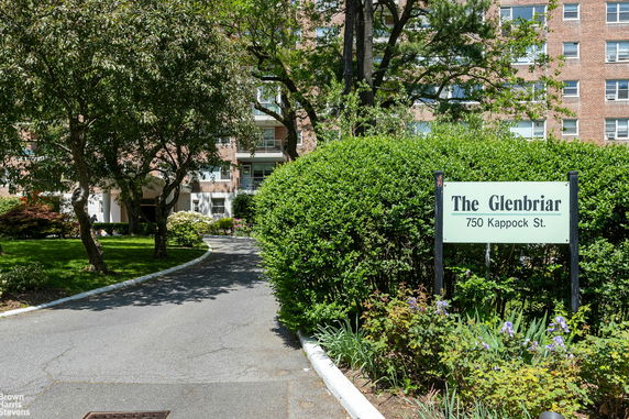 Front view of a multi-story apartment building with a pathway leading to the entrance.