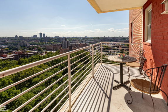 View from a balcony with a table and chairs overlooking a cityscape.