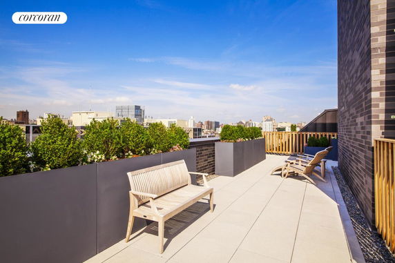 Rooftop with benches, planters, and a view of surrounding buildings.