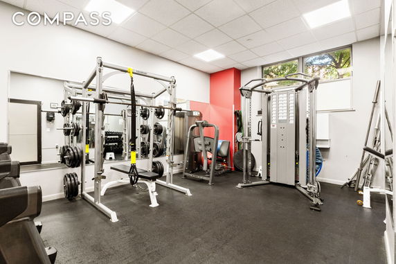 Indoor gym area with various exercise equipment, including weight machines and free weights.