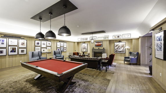 Interior view of a recreation area with a pool table, seating, and framed artwork on the walls.