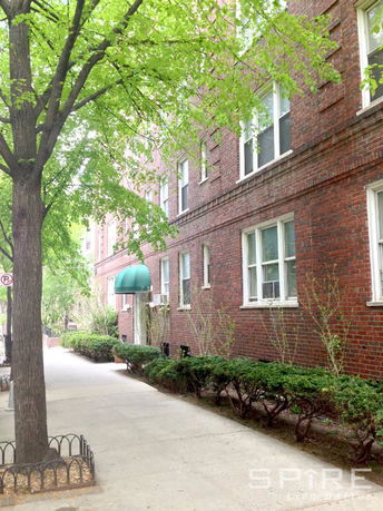 Side view of a brick apartment building with green awnings.