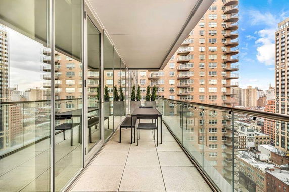 View from a balcony with glass railings overlooking city buildings.