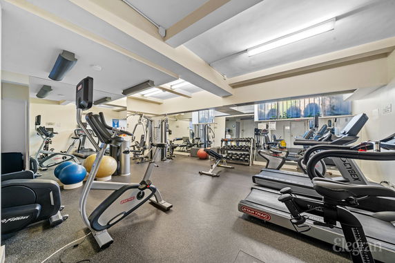 Interior view of a gym with various exercise equipment including treadmills, stationary bikes, and weights.