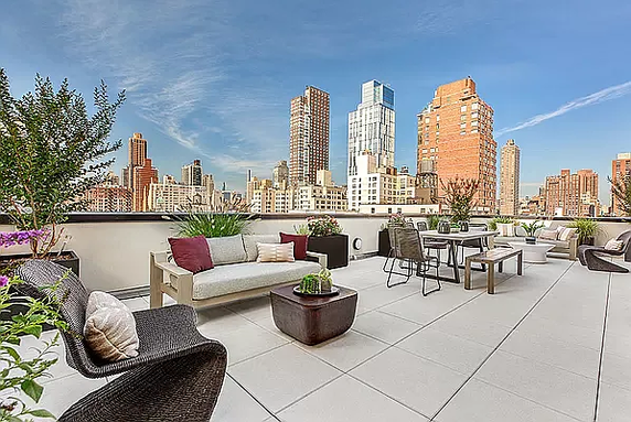 Rooftop terrace with outdoor seating and city skyline view.
