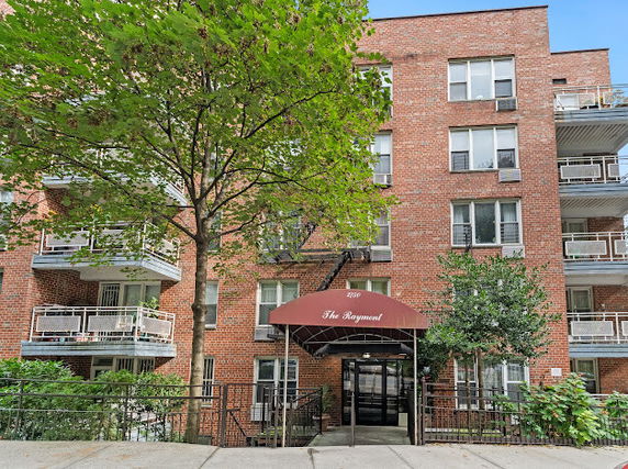 Front view of a multi-story brick apartment building with balconies.