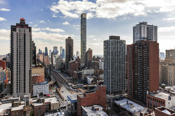 Panoramic view of a cityscape with multiple high-rise buildings and a bridge in the foreground.
