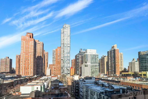 Panoramic view of a city skyline with tall buildings under a blue sky.