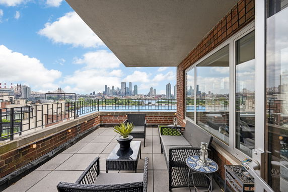 Outdoor balcony with seating offering a panoramic view of city skyline.