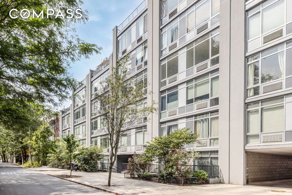 Front view of a modern multi-story apartment building with large windows and surrounding trees.