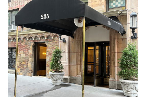 Front view of a building entrance with a black canopy and decorative potted plants.