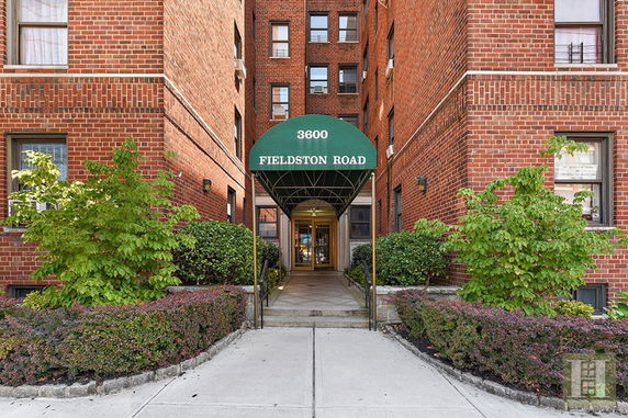 Entrance of a brick apartment building with a green awning.