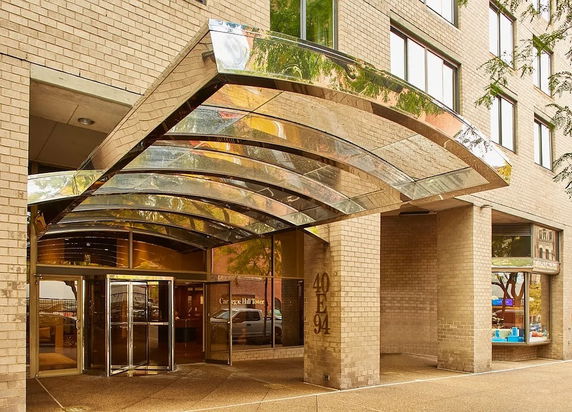 Front view of a building entrance with a glass canopy and brick facade.